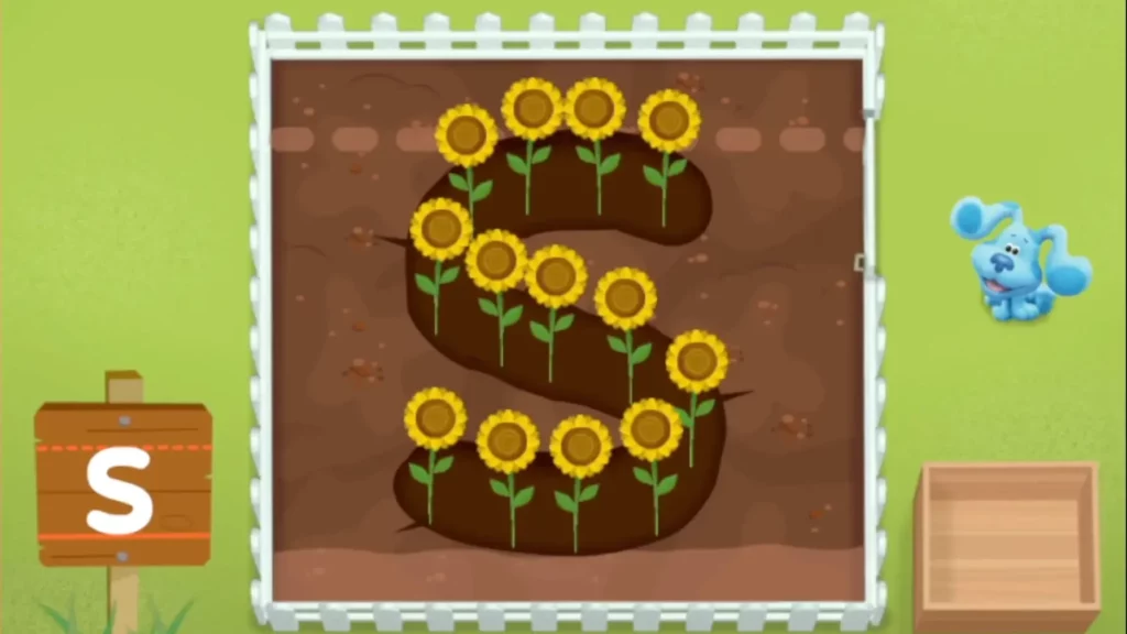 Screenshot of top down view of a plot of dirt with the letter S dug out, with sunflowers growing inside the letter.